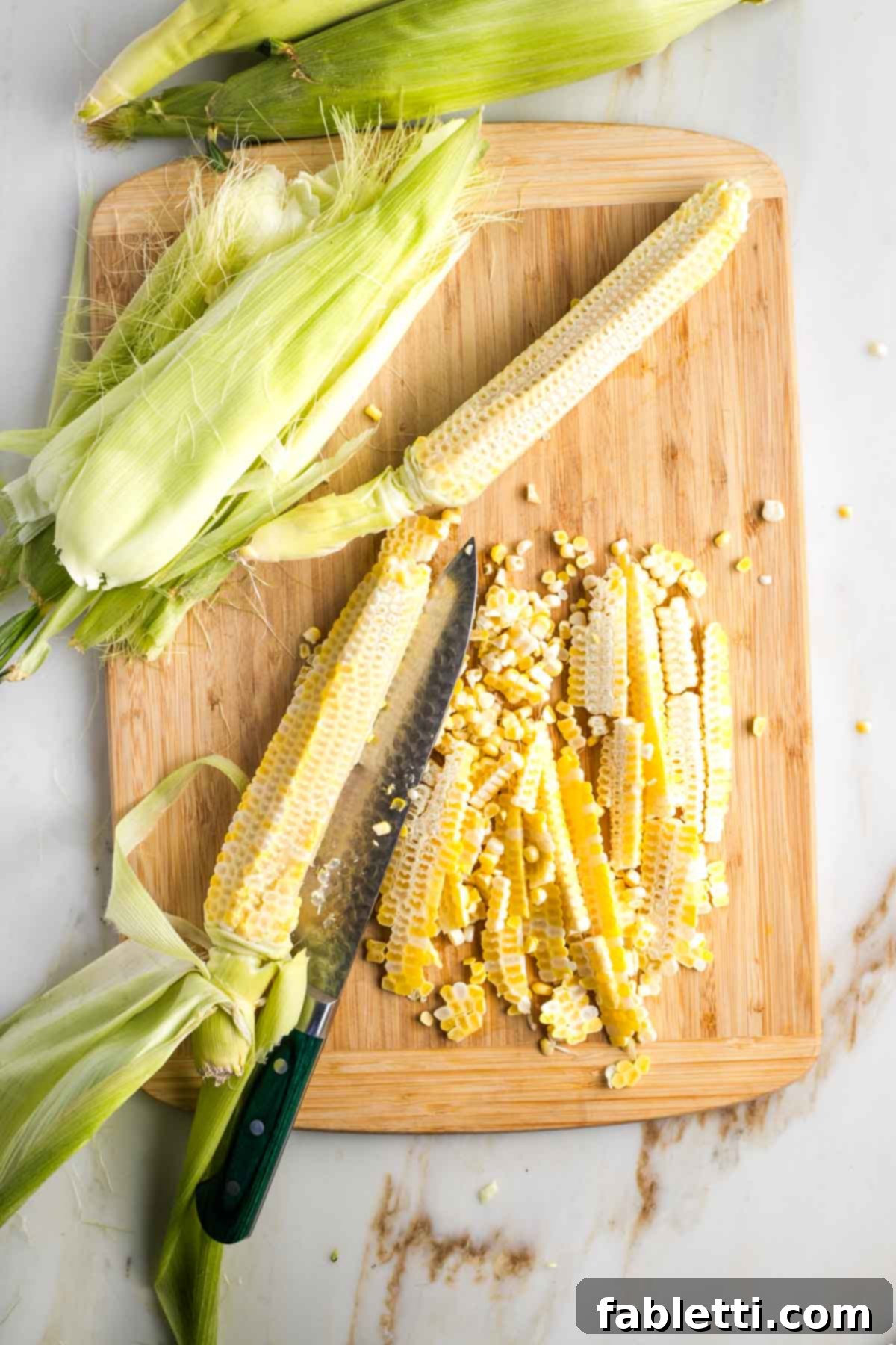 Zesty Israeli Corn and Pickle Salad 6 Several corn cobs, now stripped of their kernels, resting on a cutting board, demonstrating that all kernels have been successfully removed.