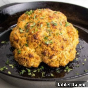 Golden brown whole roasted cauliflower, sprinkled with fresh herbs.