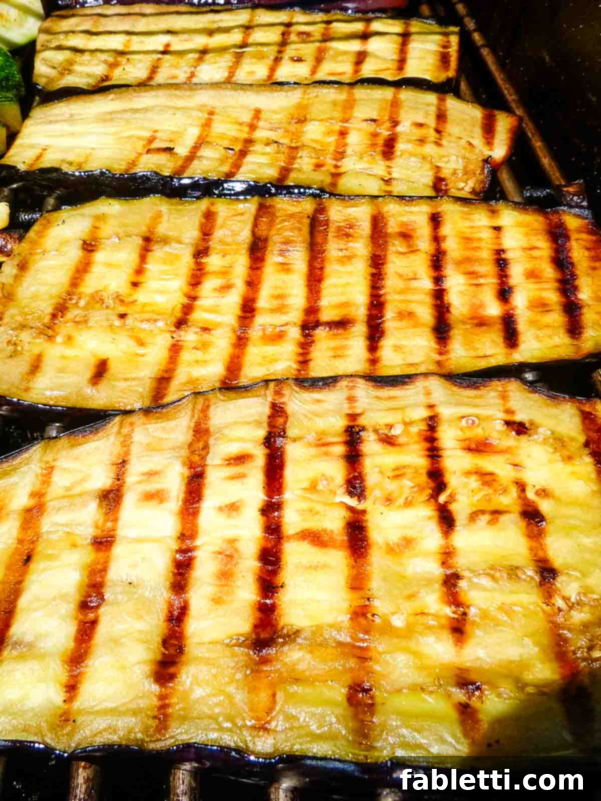 Smoky Grilled Ratatouille Salad 4 Sliced vegetables like zucchini, eggplant, and bell pepper are carefully placed in a single layer on a hot grill.