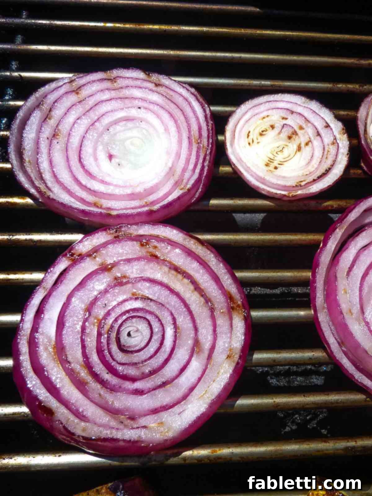 Smoky Grilled Ratatouille Salad 5 A hand uses tongs to flip grilled vegetables, revealing beautiful char marks on one side.
