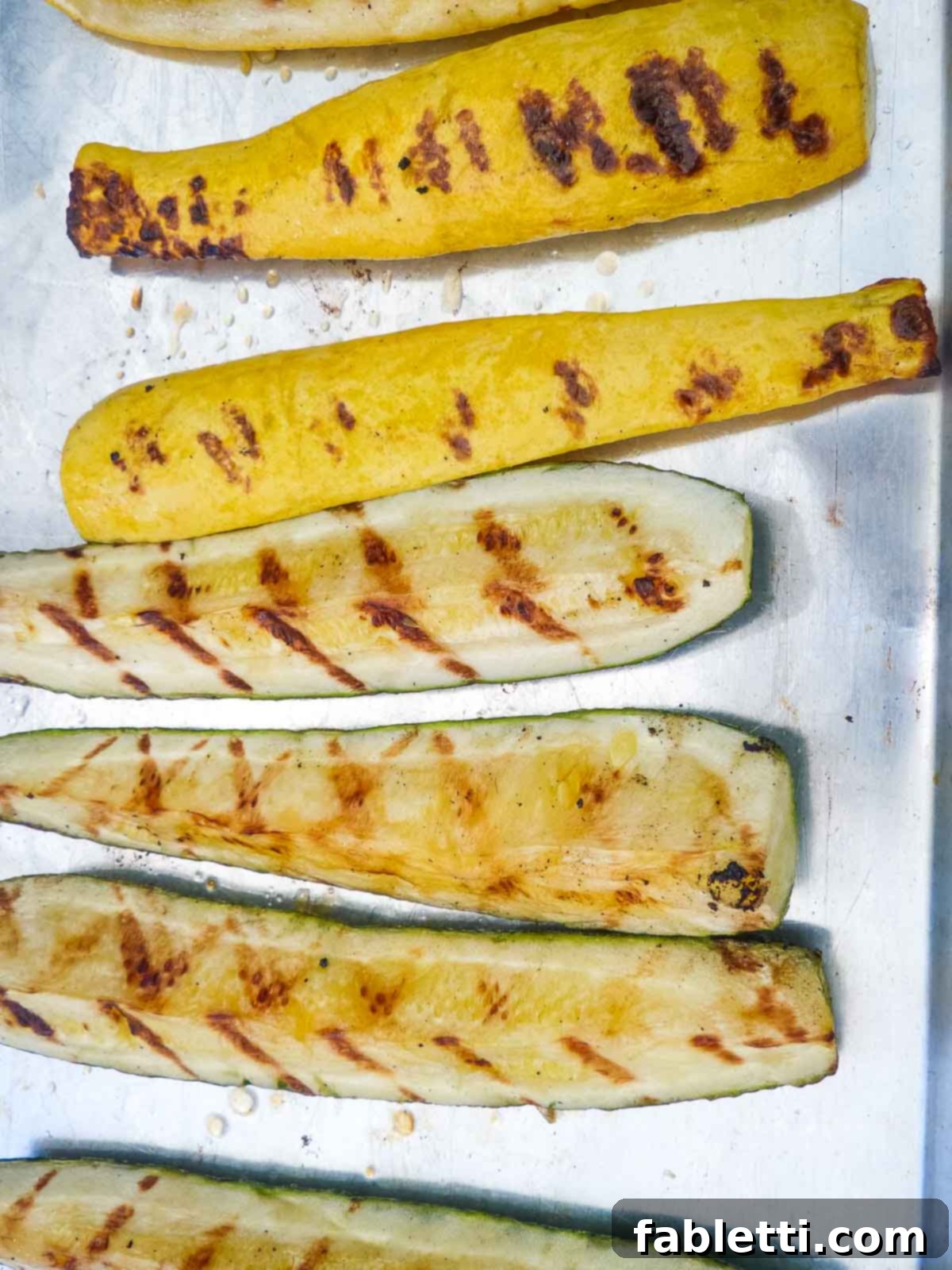 Smoky Grilled Ratatouille Salad 6 Tender, cooked grilled vegetables are being removed from the grill with tongs and placed onto a platter.