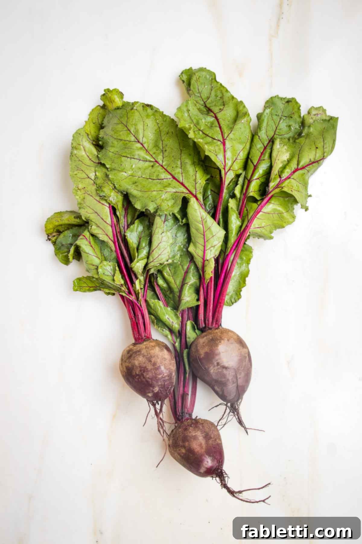Balsamic Roasted Beet Salad 3 Three large red beets with the beet greens still attached to the beet root.