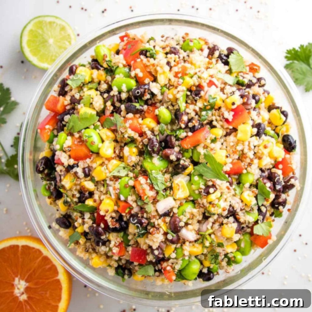 Zesty Southwest Quinoa Salad 3 large glass bowl filled with colorful quinoa salad. half a lime, half an orange and fresh cilantro on the white counter surrounding the bowl.