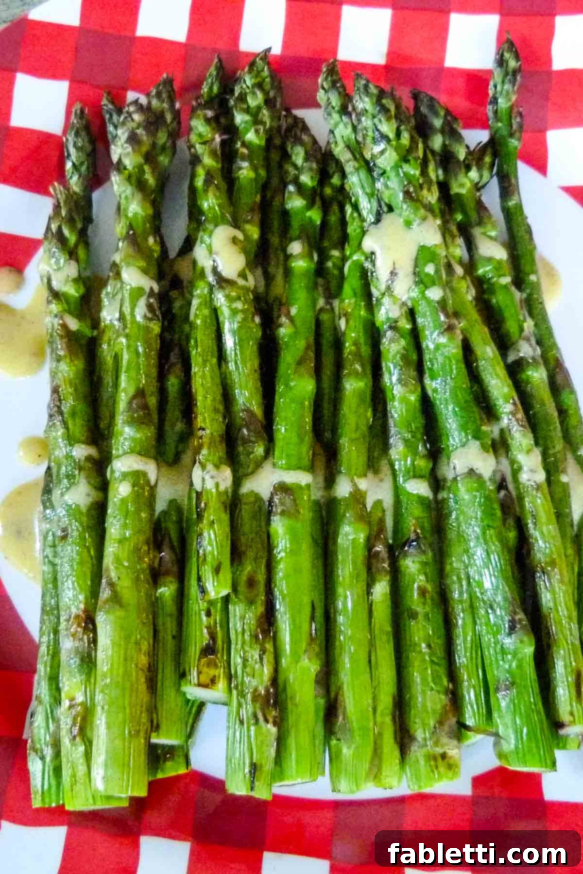 Smoked Asparagus with Dijon Glaze 2 A plate of perfectly grilled asparagus spears, lightly drizzled with a vibrant, creamy mustard sauce, garnished and ready to be served as a delightful spring or summer side dish.