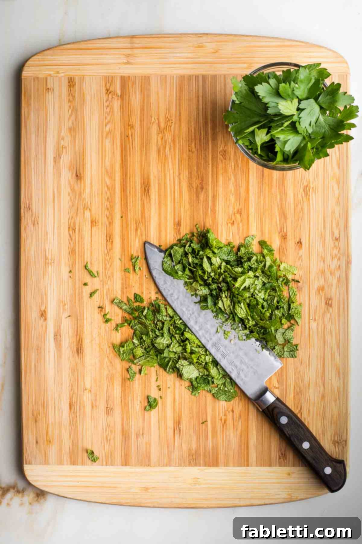 Sweet Parsnip Gluten-Free Tabbouleh 7 Stack of fresh mint leaves being sliced thin and a small dish with fresh parsley leaves.