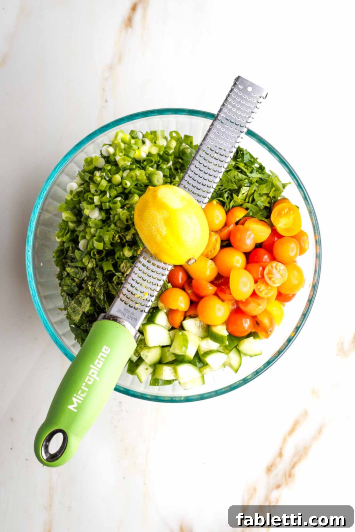 Sweet Parsnip Gluten-Free Tabbouleh 12 Zesting a lemon over a large bowl filled with chopped veggies and tomatoes.