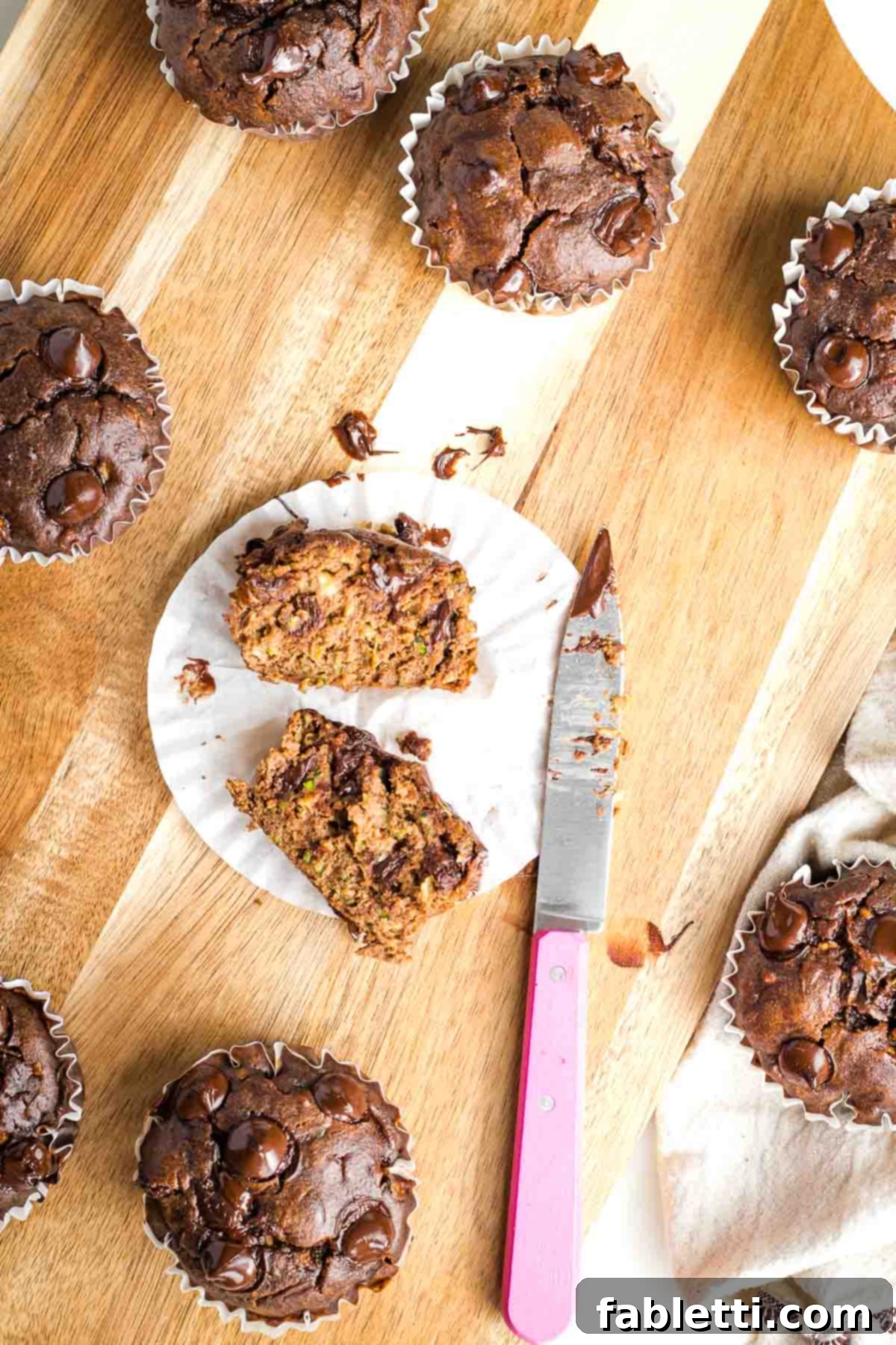 Decadent Double Chocolate Zucchini Muffins 2 Chocolate muffin with chocolate chips cut in half in the paper wrapper.