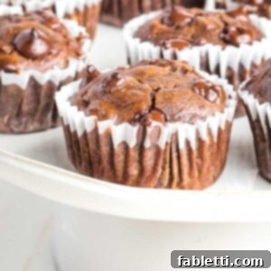 Decadent Double Chocolate Zucchini Muffins 14 Chocolate muffin with chocolate chips in a white cupcake liner.