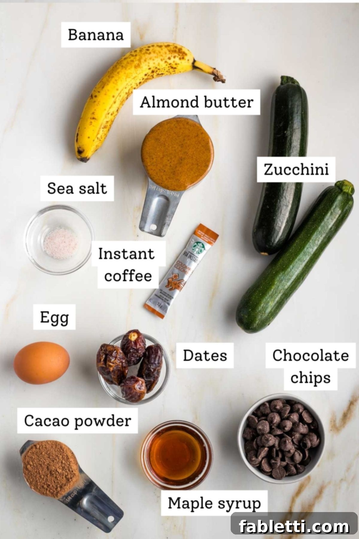 Decadent Double Chocolate Zucchini Muffins 4 Labeled ingredients: banana, almond butter, zucchini, salt, egg, dates, maple syrup, cacao, instant coffee and chocolate chips.