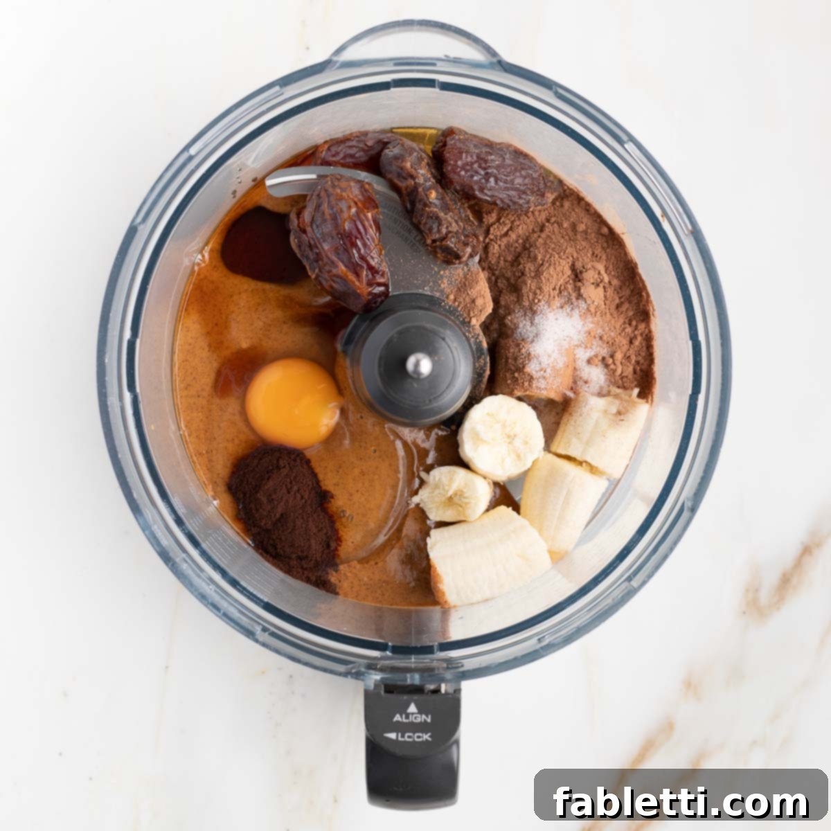 Decadent Double Chocolate Zucchini Muffins 6 Ingredients in a food processor bowl: banana, egg, cocoa powder, dates.