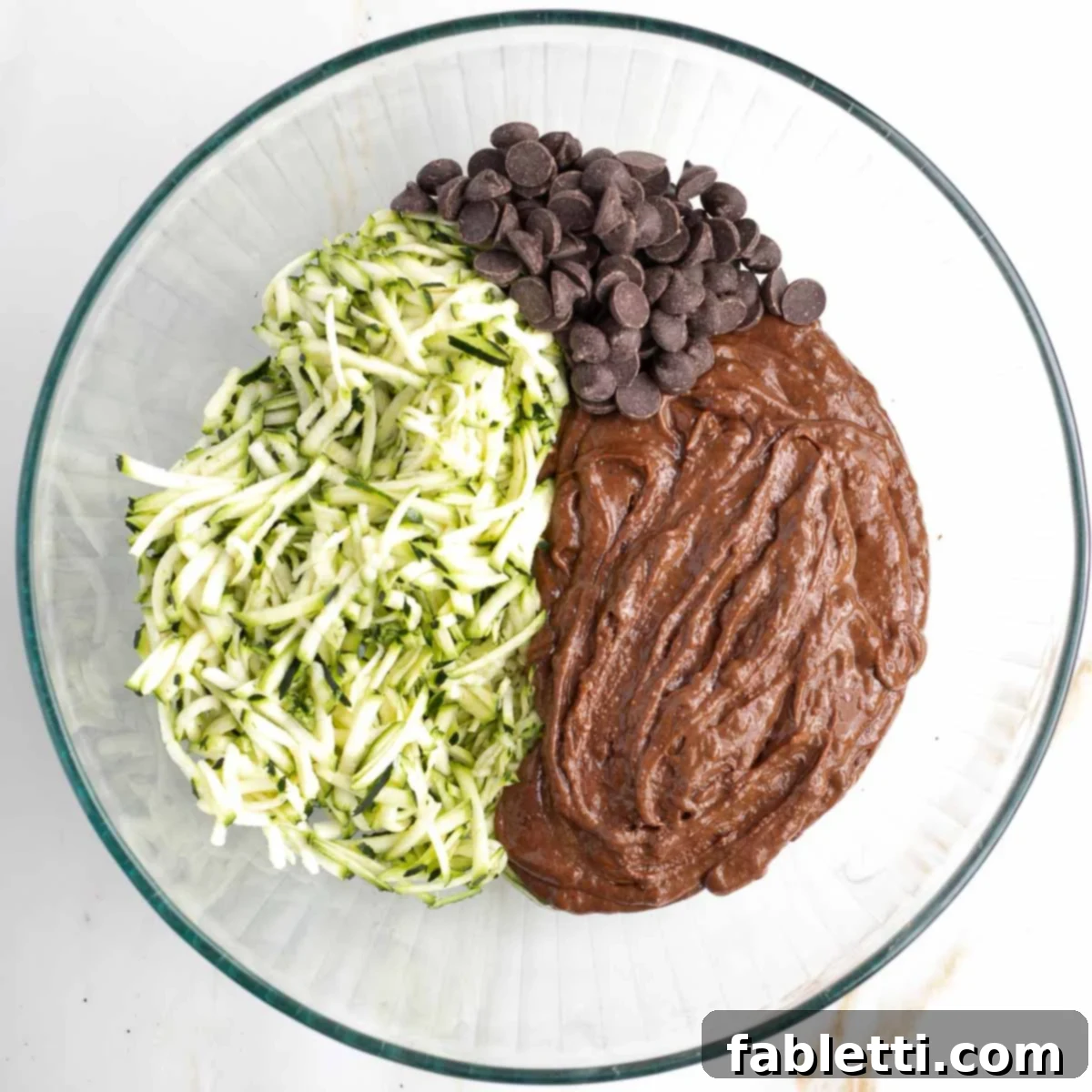 Decadent Double Chocolate Zucchini Muffins 8 Chocolate batter, chocolate chips and shredded zucchini in a large glass mixing bowl.