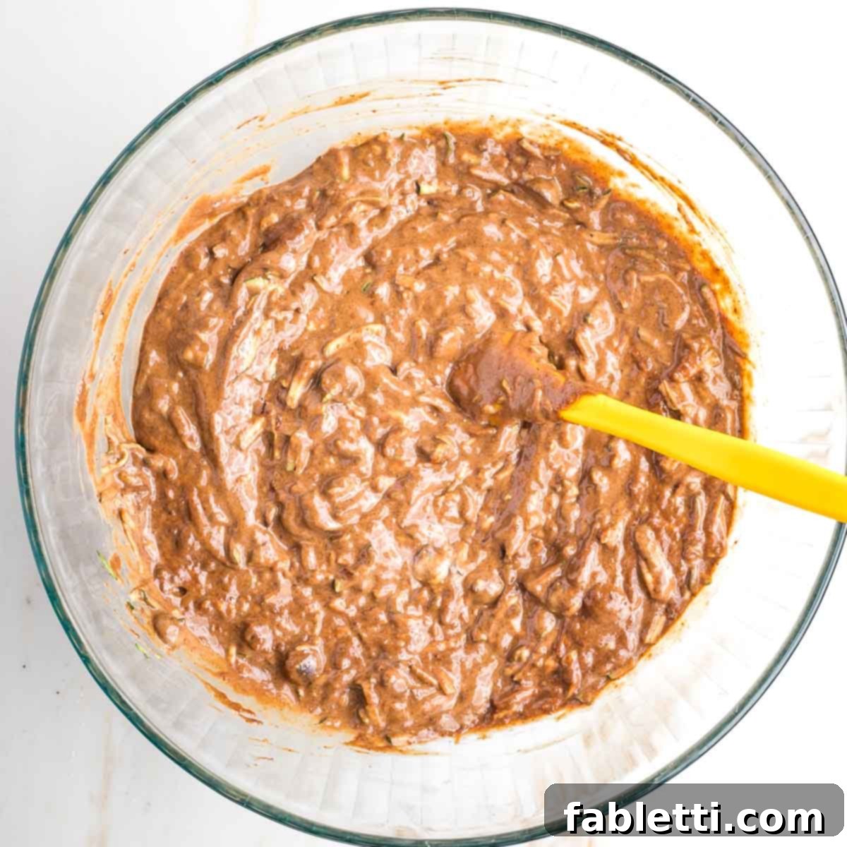 Decadent Double Chocolate Zucchini Muffins 9 Chocolate batter in a large bowl with chunks of chocolate and shredded zucchini.