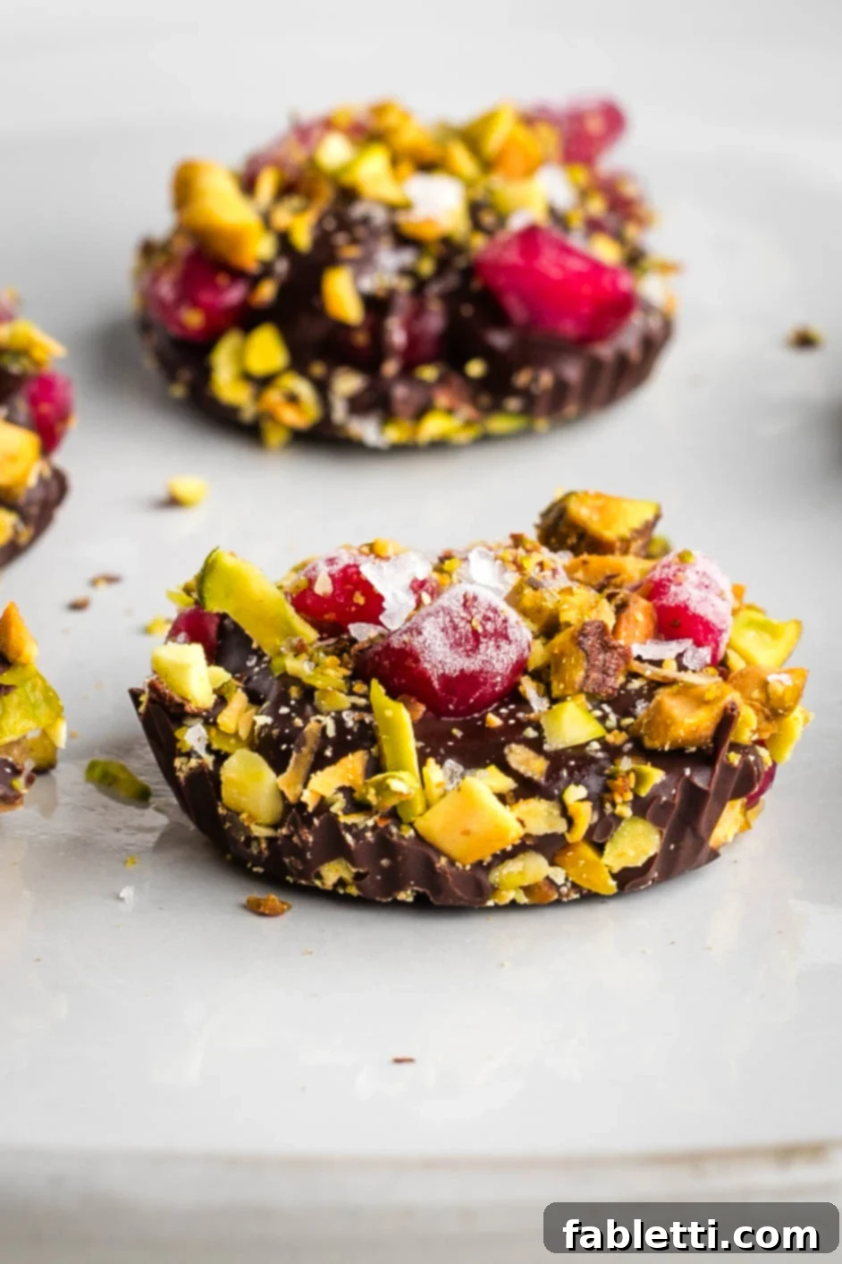 Jeweled Chocolate Peanut Butter Cups 2 Dark chocolate cups generously topped with ruby red pomegranate seeds and bright green pistachios.
