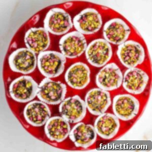 Jeweled Chocolate Peanut Butter Cups 14 Red cake plate filled with chocolate peanut butter cups with pomegranate and pistachios in white liners.
