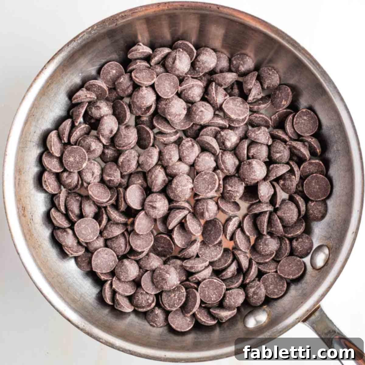 Jeweled Chocolate Peanut Butter Cups 5 Dark chocolate chips in a small stainless steel skillet, ready to be melted.