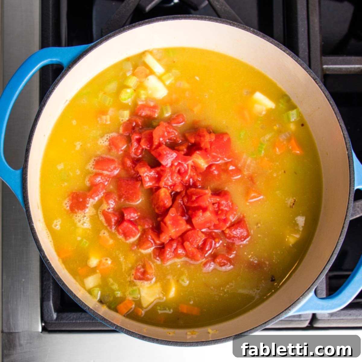 Wholesome Plant-Based Lentil Soup 12 Dutch oven with soup, including chopped tomatoes and chunky vegetables.