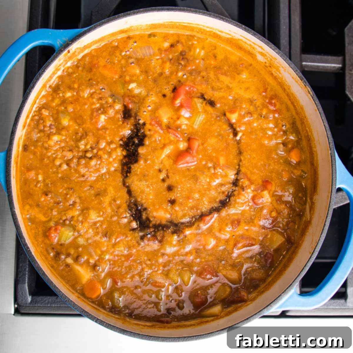 Wholesome Plant-Based Lentil Soup 15 Blended lentil soup in a blue dutch oven, with a swirl of balsamic on top.