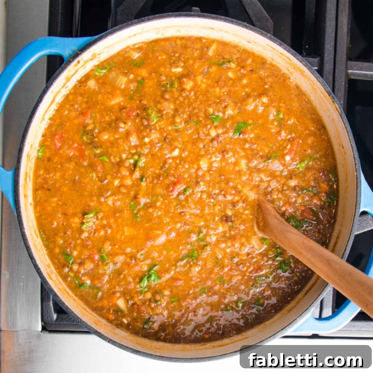 Wholesome Plant-Based Lentil Soup 17 Dutch oven with chunky lentil soup and wilted kale.