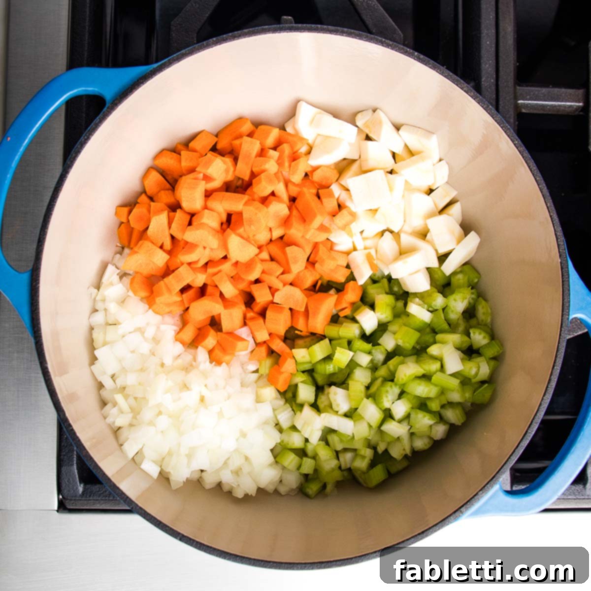 Wholesome Plant-Based Lentil Soup 6 Dutch oven filled with sections of diced carrots, onions, celery and parsnips.