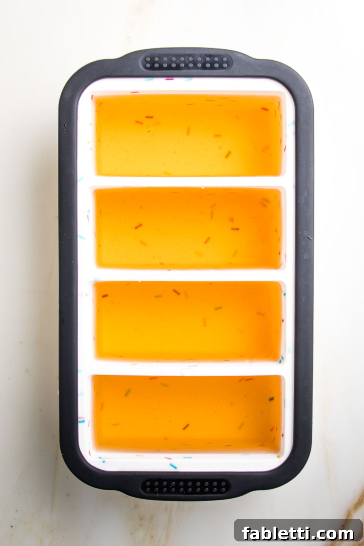 Silicone ice cube mold filled with vegetable broth in 4- 1 cup sections.