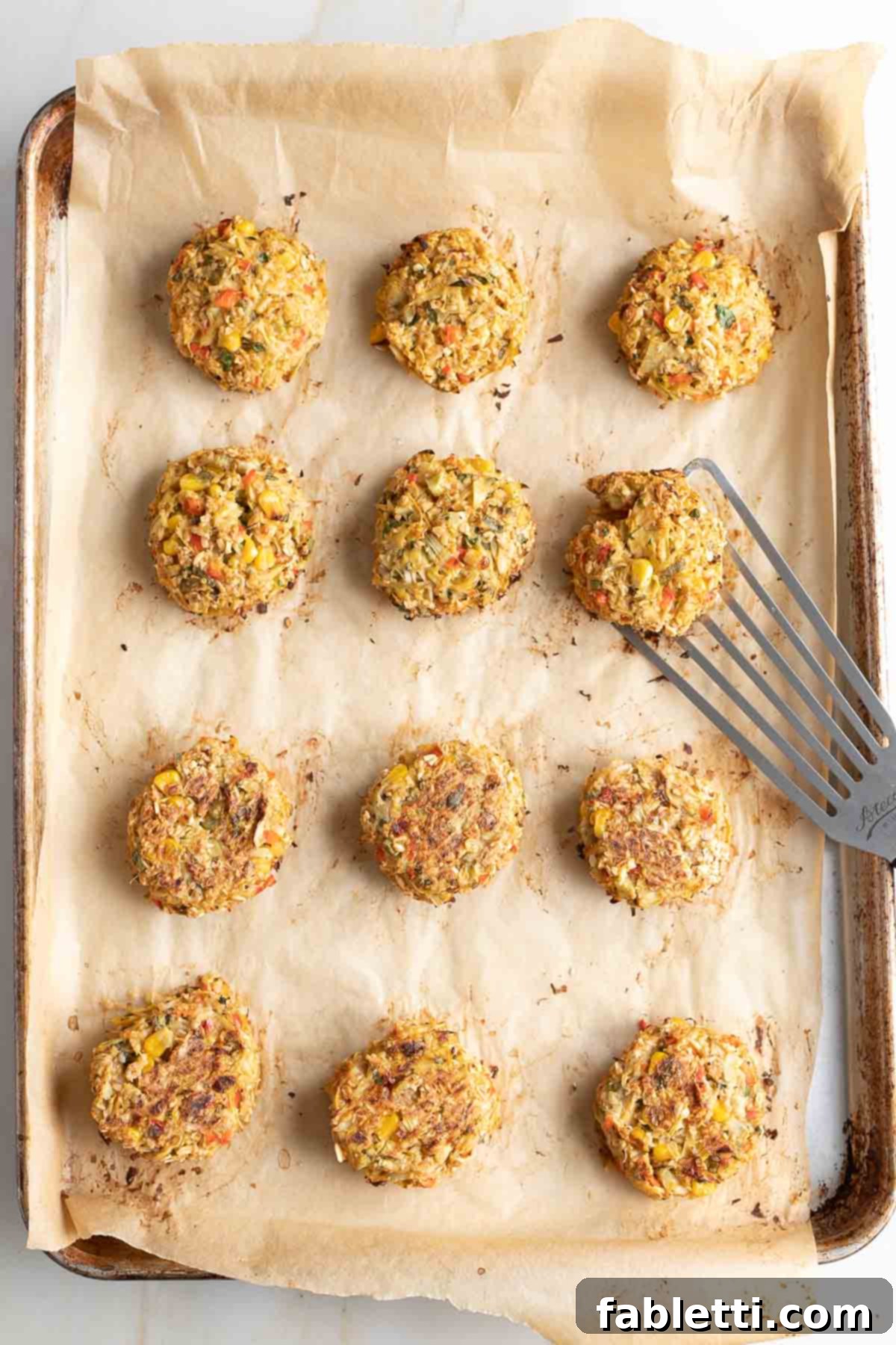 Flipping vegan crab cakes to other side during baking.