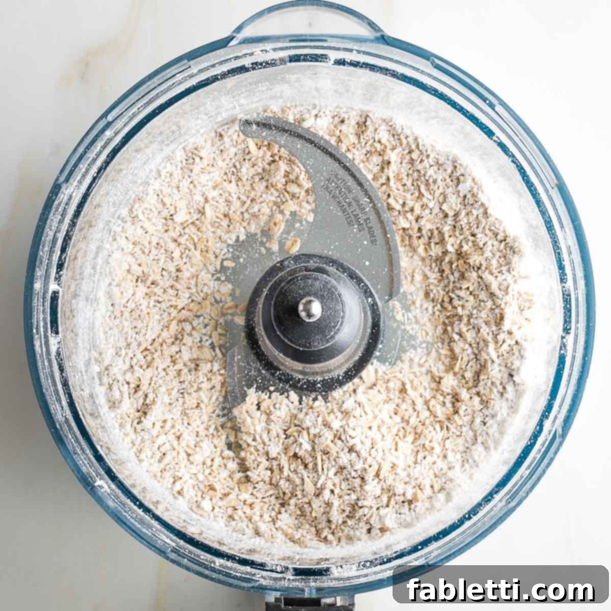 Coarsely ground oats in the bowl of a food processor.