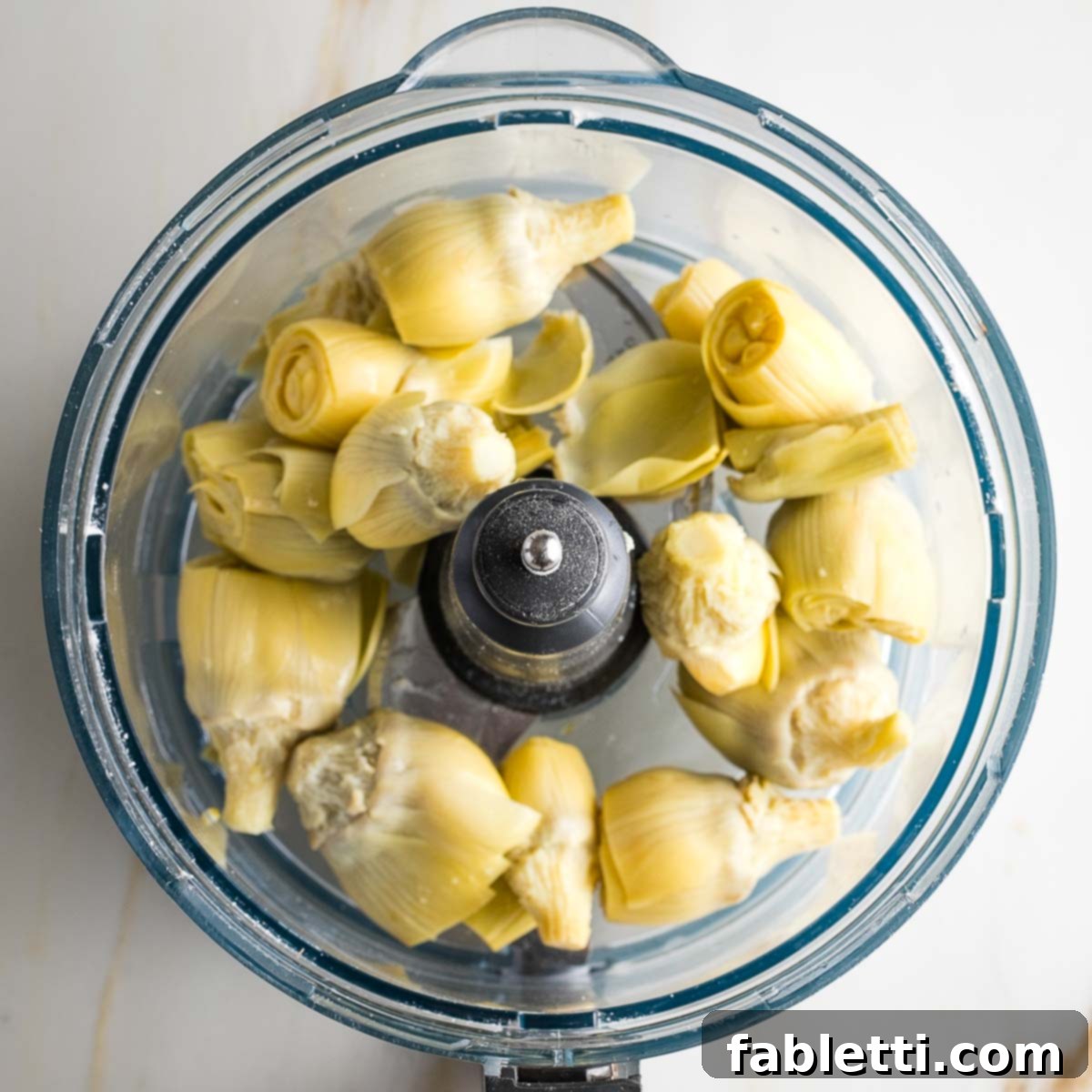 Artichoke hearts in the bowl of a food processor.