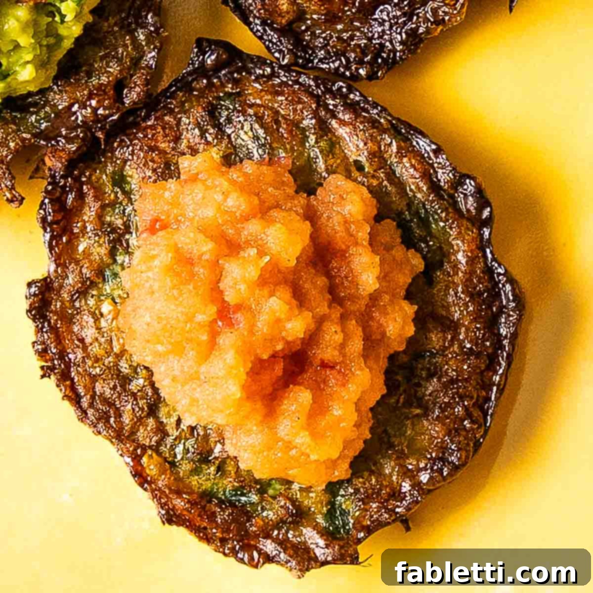 Oven-Baked Crispy Brussels Sprout Latkes 13 A perfectly crispy Brussels sprouts latke, beautifully topped with a spoonful of homemade pink applesauce, ready to be savored.