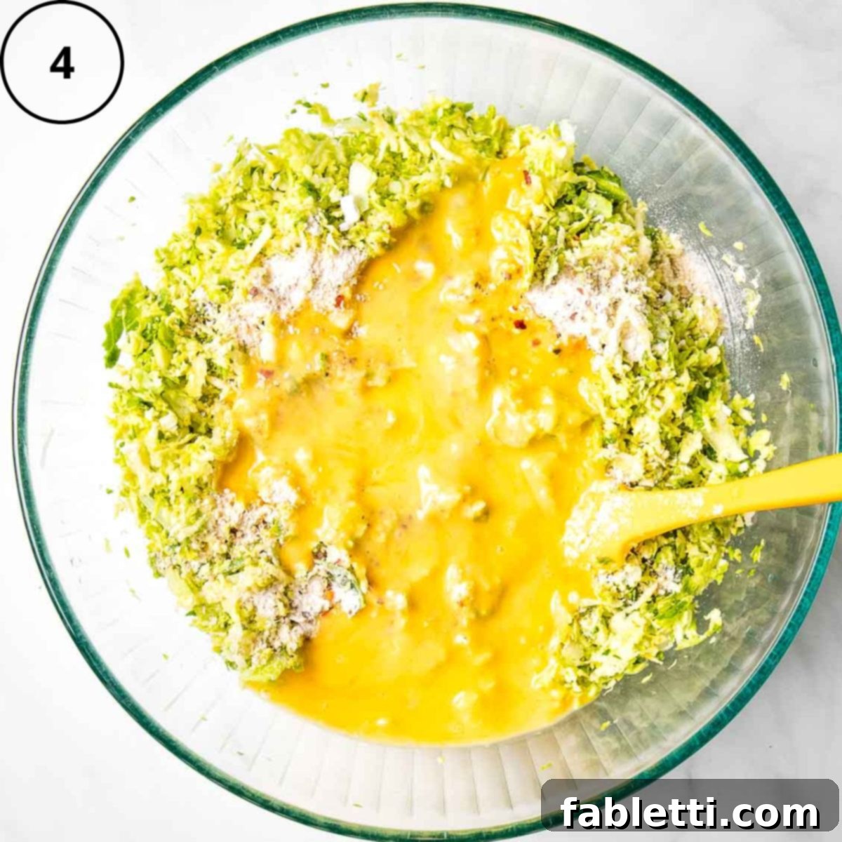 Oven-Baked Crispy Brussels Sprout Latkes 7 The vibrant shredded vegetable and oat flour mixture topped with freshly scrambled raw eggs, ready to be incorporated.