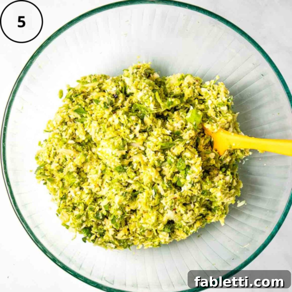 Oven-Baked Crispy Brussels Sprout Latkes 8 A homogeneous and well-combined Brussels sprouts latke mixture, showcasing a consistent texture in a glass bowl.