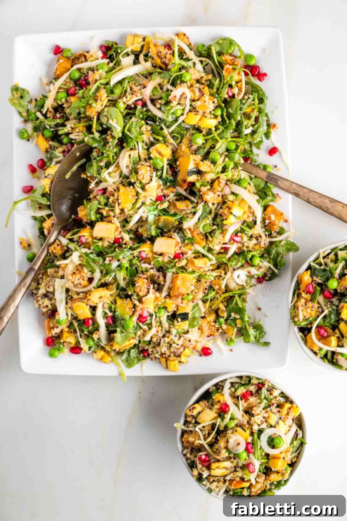 Colorful chopped salad with roasted squash, quinoa, pomegranate seeds and frozen peas.