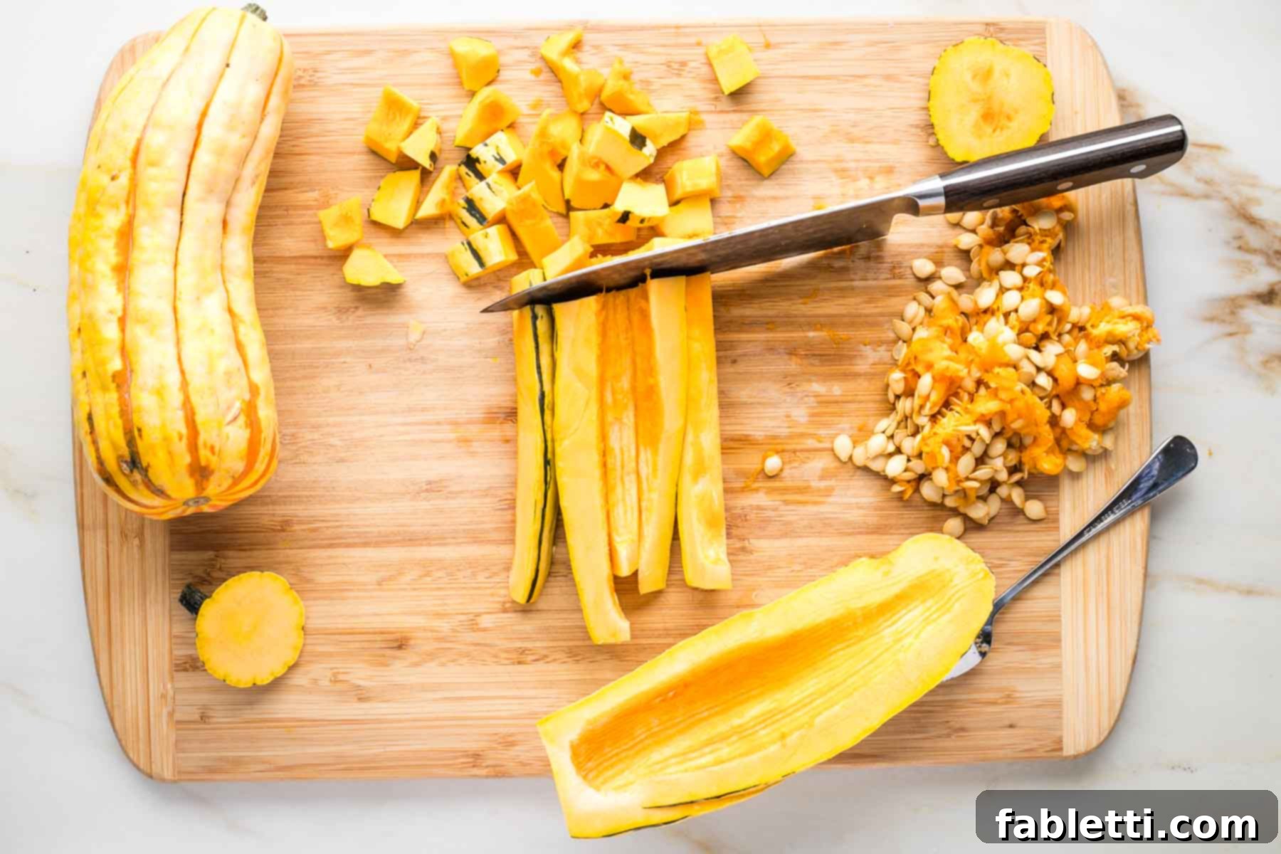 Delicata squash cut in half lengthwise, seeds scooped out and showing how to cut long and then across for small dice.
