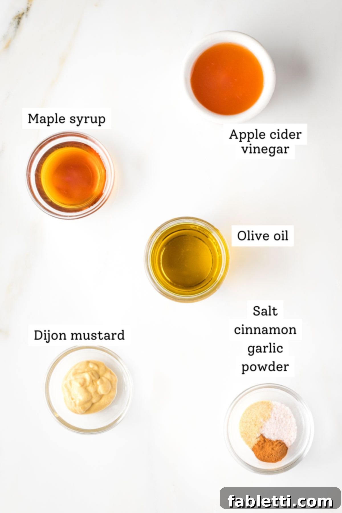 Labeled ingredients for maple vinaigrette: apple cider vinegar, maple syrup, olive oil, spices, dijon mustard.