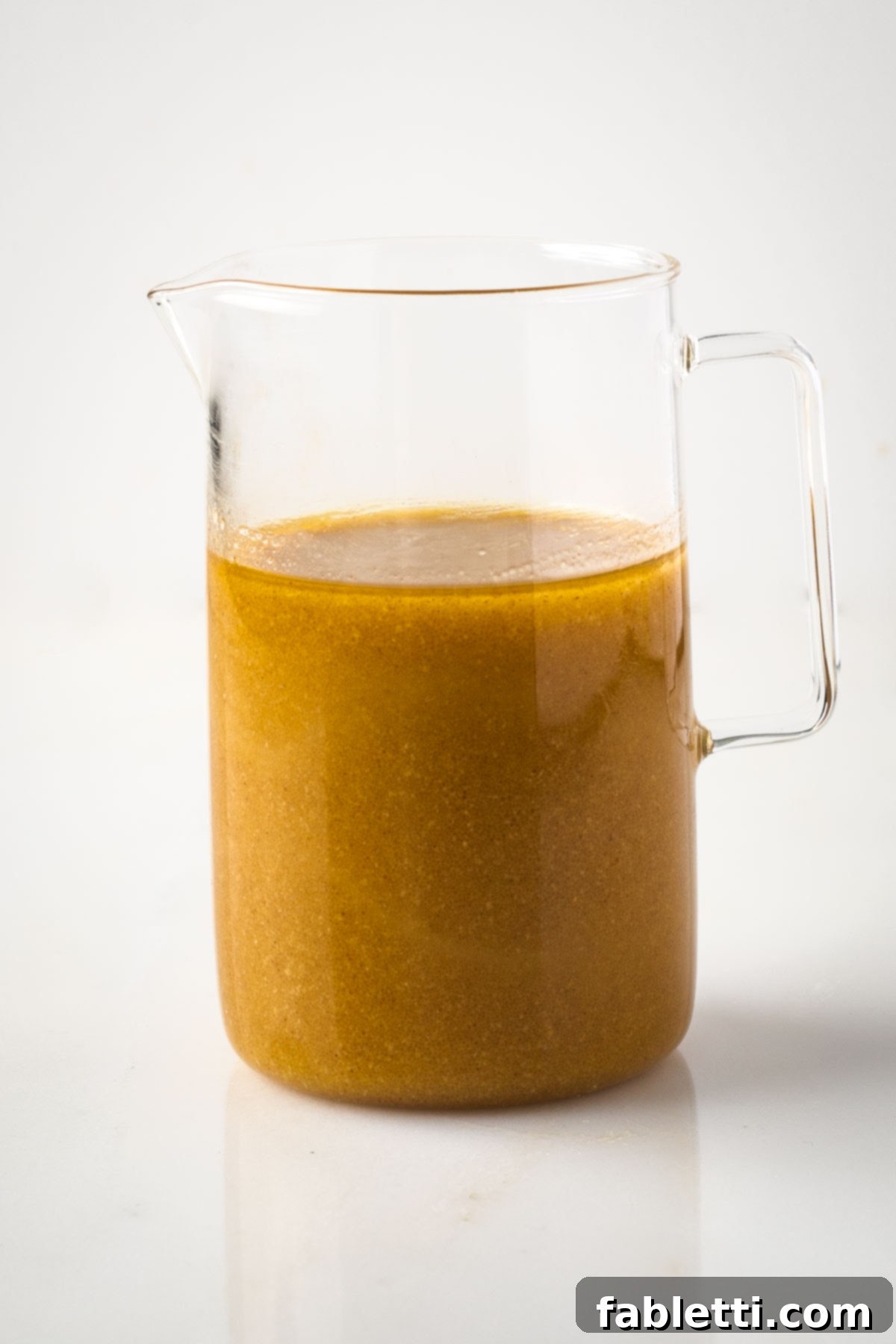 Maple mustard vinaigrette in a small glass pitcher.
