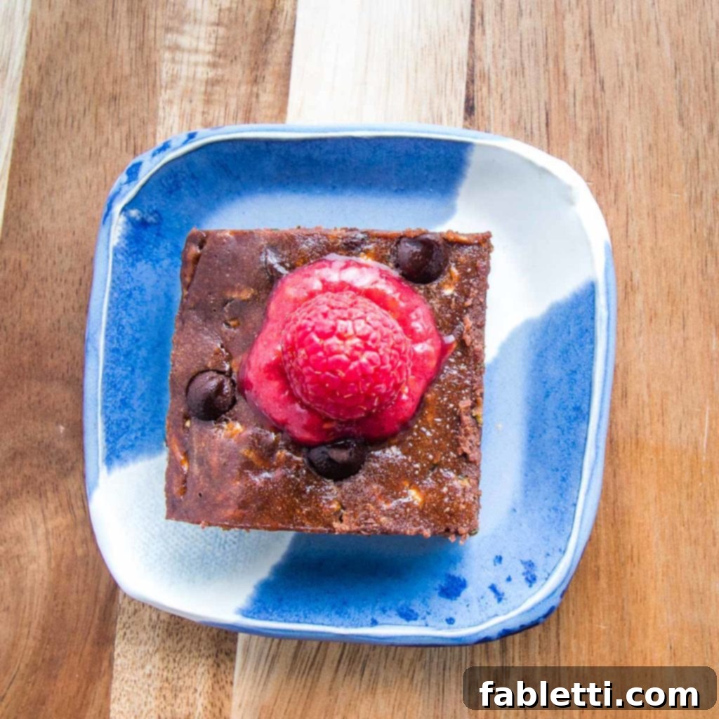 Secret Garden Chocolate Brownies 2 Super moist chocolate zucchini brownie on a bright blue plate, generously topped with a rich raspberry sauce.