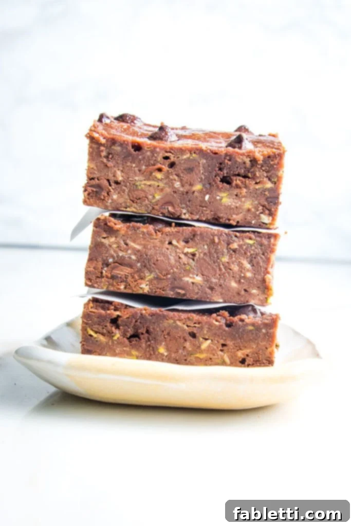 Secret Garden Chocolate Brownies 5 A delectable stack of chocolate zucchini brownies, generously sprinkled with dark chocolate chips.