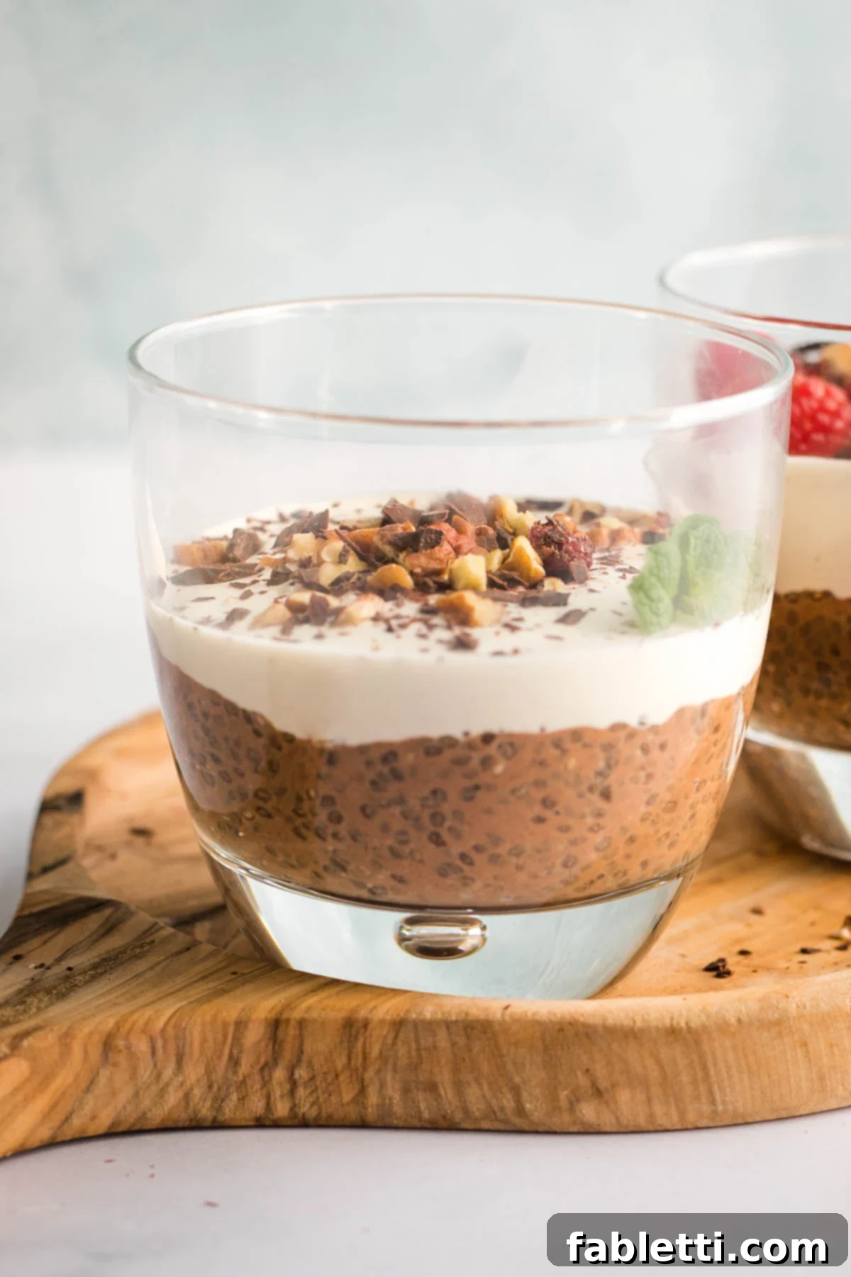 Effortless Chocolate Chia Pudding Bliss 2 Chocolate chia pudding in the bottom of a glass, topped with cream and chopped nuts.