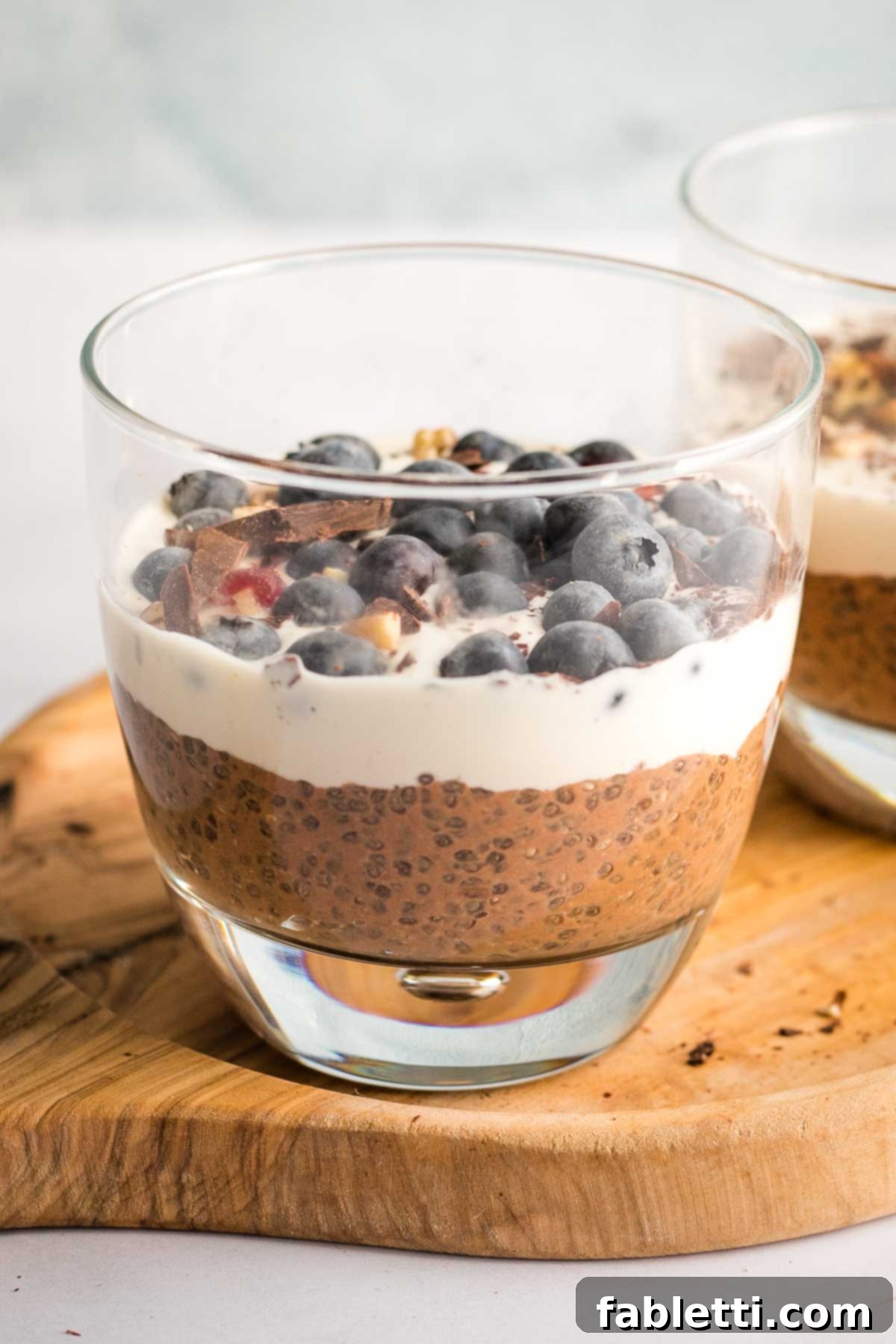Effortless Chocolate Chia Pudding Bliss 15 Chocolate chia pudding in a glass, topped with cream and blueberries.
