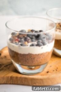 Effortless Chocolate Chia Pudding Bliss 16 Chocolate chia pudding in a glass, topped with cream and blueberries.
