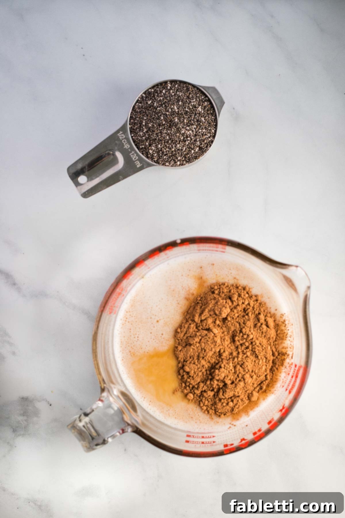 Effortless Chocolate Chia Pudding Bliss 5 Dry measuring cup with chia seeds and liquid cup with plant-based milk, maple syrup and cacao powder.