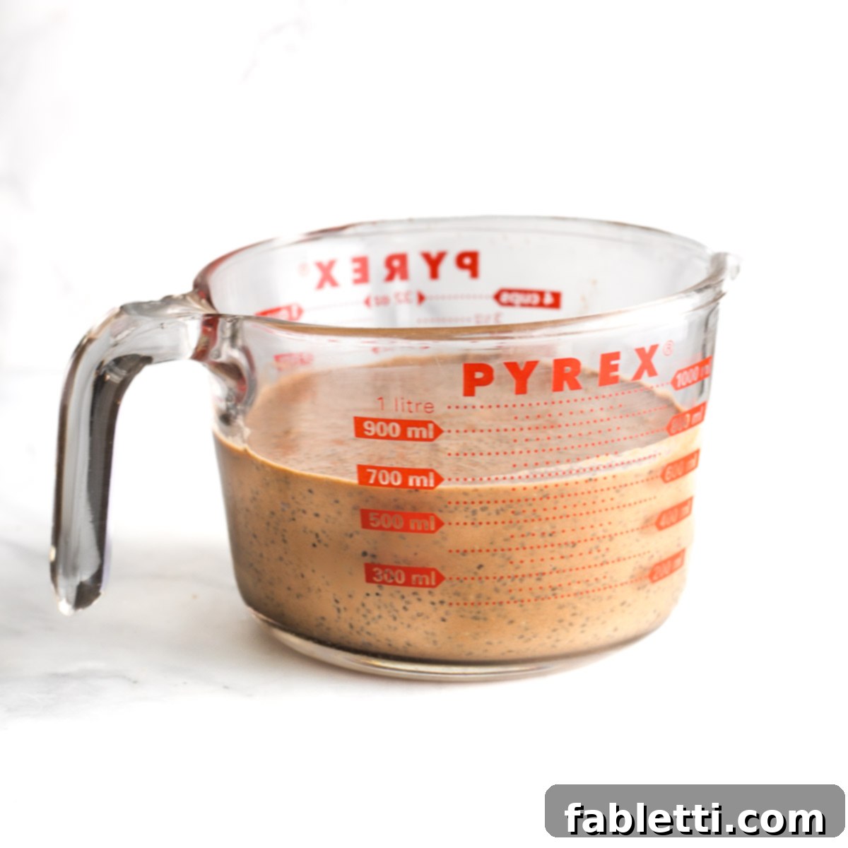 Effortless Chocolate Chia Pudding Bliss 9 Pyrex measuring cup with chocolate mixture and floating chia seeds throughout.