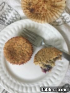 Bright Gluten-Free Blueberry Lemon Poppy Seed Muffins 9 A delicious blueberry lemon poppyseed muffin, cut open on a white plate.