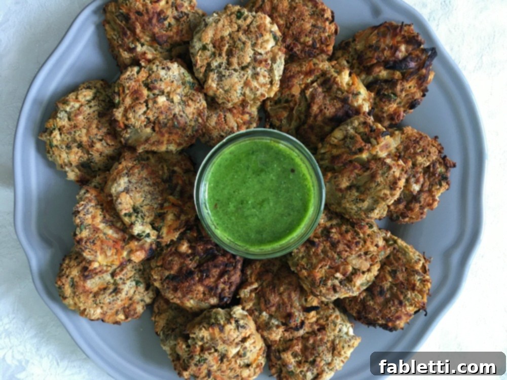 Hearty Homemade White Bean Veggie Burgers 15 A round white plate beautifully arranged with mini veggie burgers, encircling a small glass dish of vibrant green dipping sauce in the center.