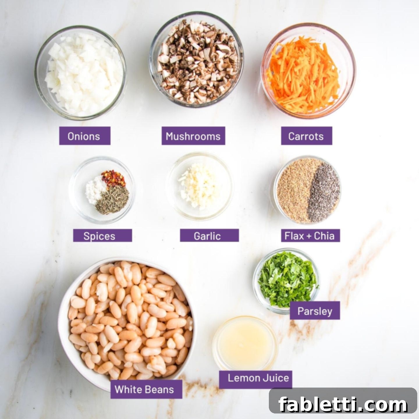 Hearty Homemade White Bean Veggie Burgers 3 Bowls of neatly arranged ingredients for veggie burgers: diced onions, chopped mushrooms, grated carrots, ground flaxseed, chia seeds, fresh garlic, assorted spices, fresh parsley, lemon juice, and a bowl of cannellini beans.