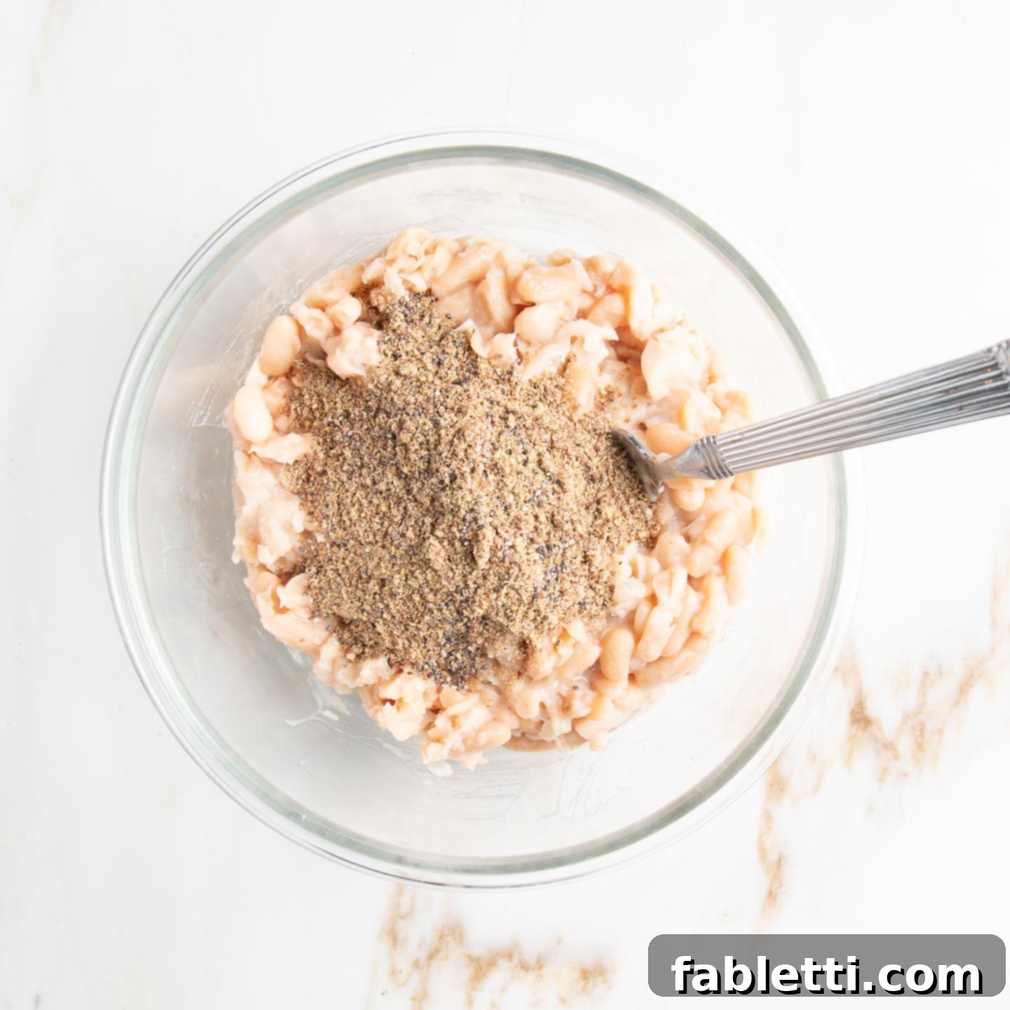 Hearty Homemade White Bean Veggie Burgers 6 The bowl of mashed beans now topped with ground flax seeds and chia seeds, ready to be thoroughly mixed.