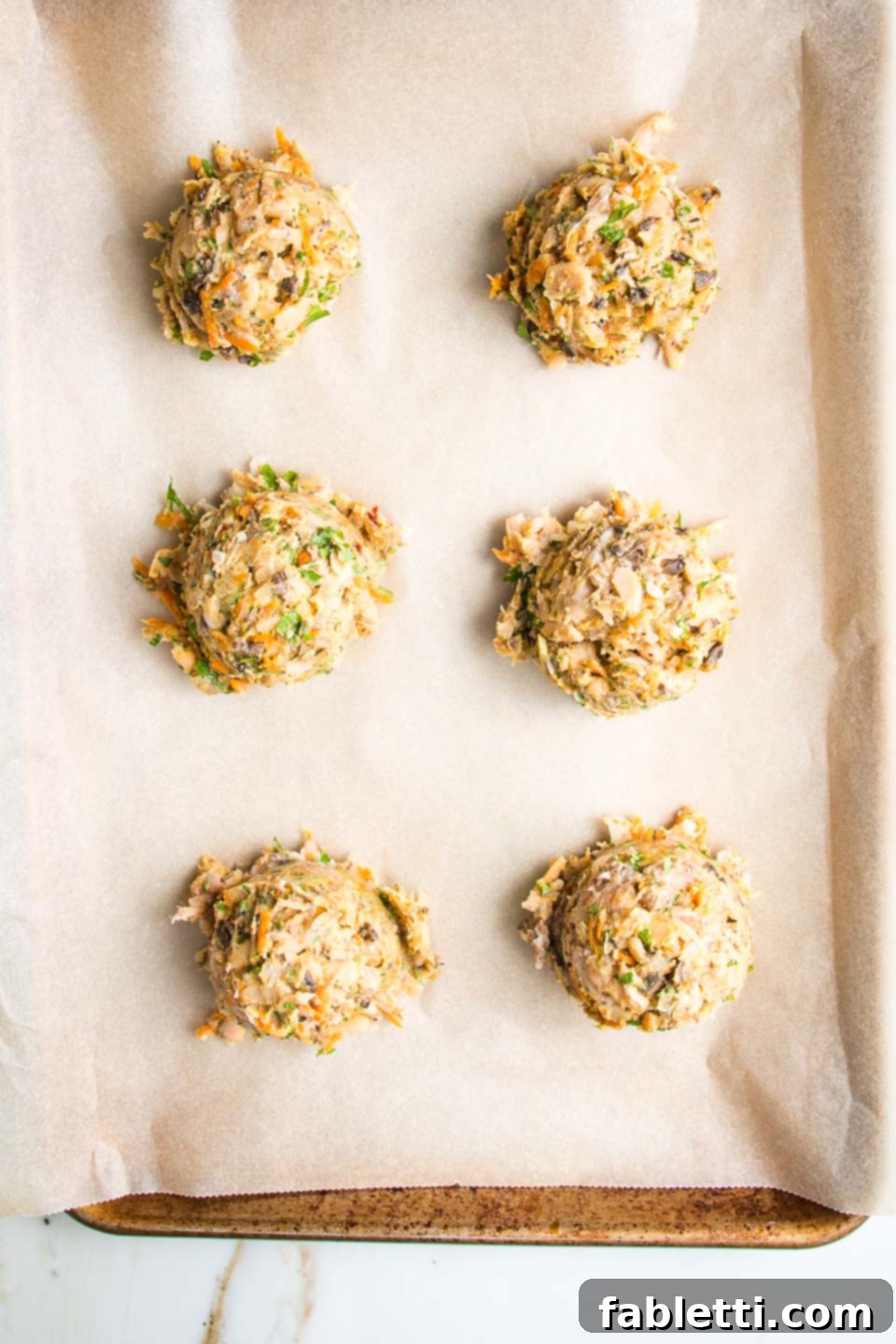 Hearty Homemade White Bean Veggie Burgers 9 Scoops of white bean burger batter arranged on a parchment-lined baking tray, ready for shaping.