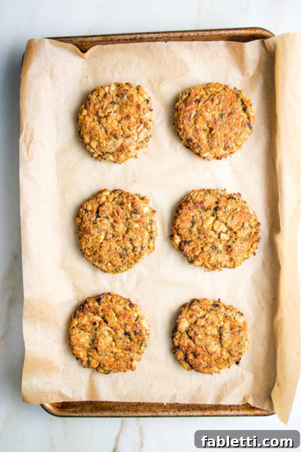 Hearty Homemade White Bean Veggie Burgers 10 Perfectly shaped white bean veggie burger patties resting on a parchment-lined baking tray, ready for the oven.
