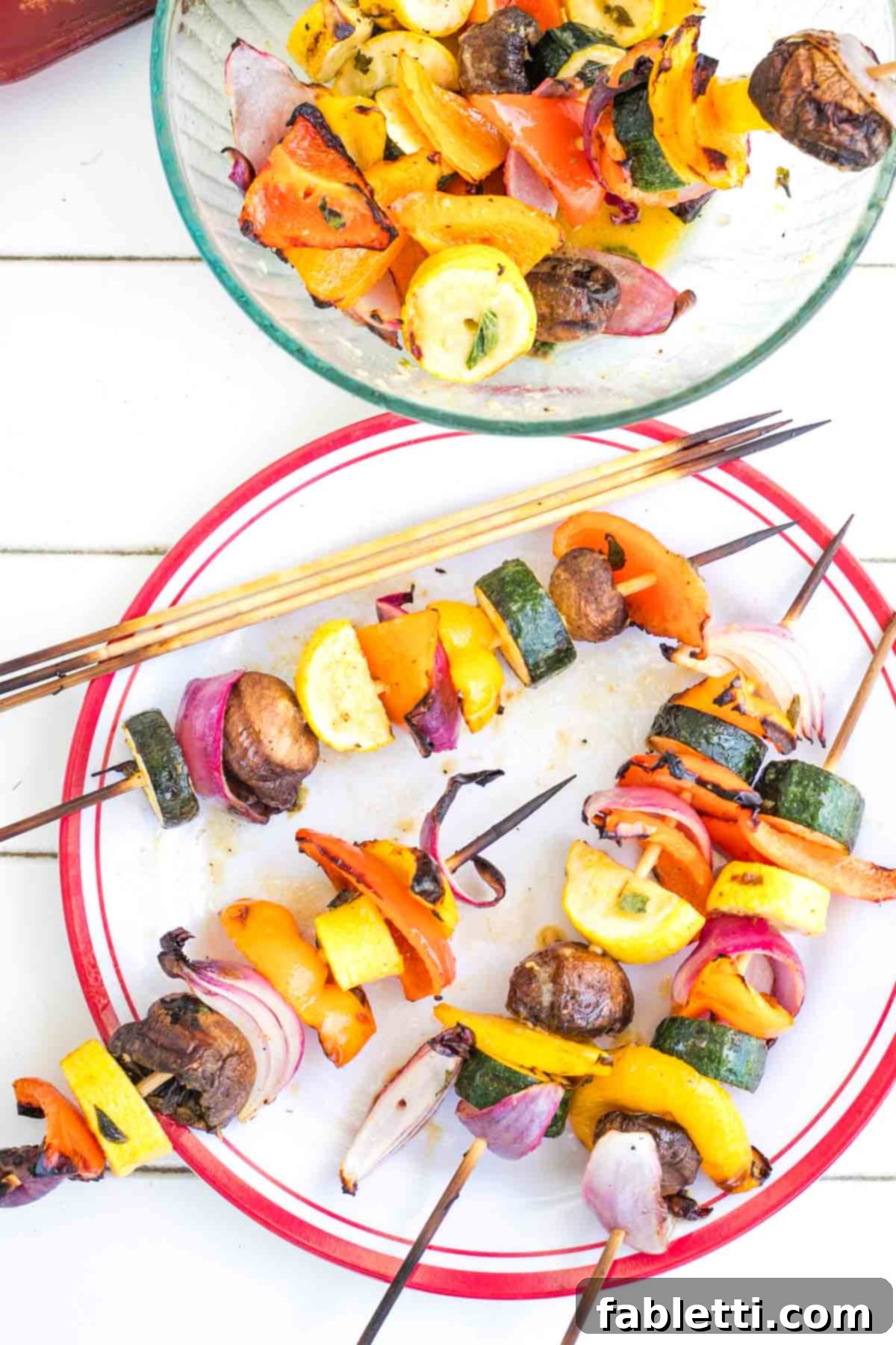Vibrant Mediterranean Veggie Skewers 11 A serving plate with colorful grilled vegetable kabobs, some still on skewers and some vegetables removed and placed in a bowl, ready to be enjoyed.
