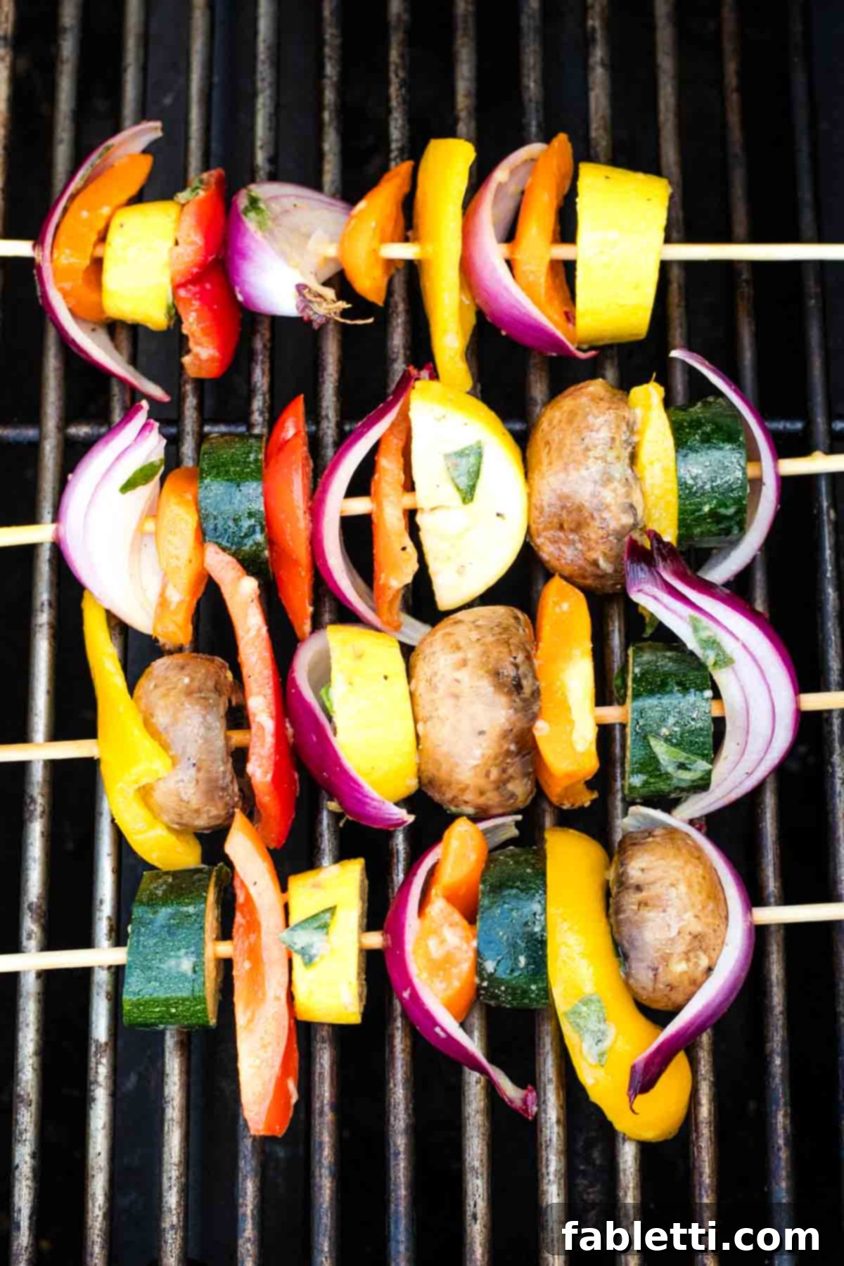 Vibrant Mediterranean Veggie Skewers 9 Several skewers of colorful, marinated vegetables placed directly on a hot grill, showing the start of grilling.