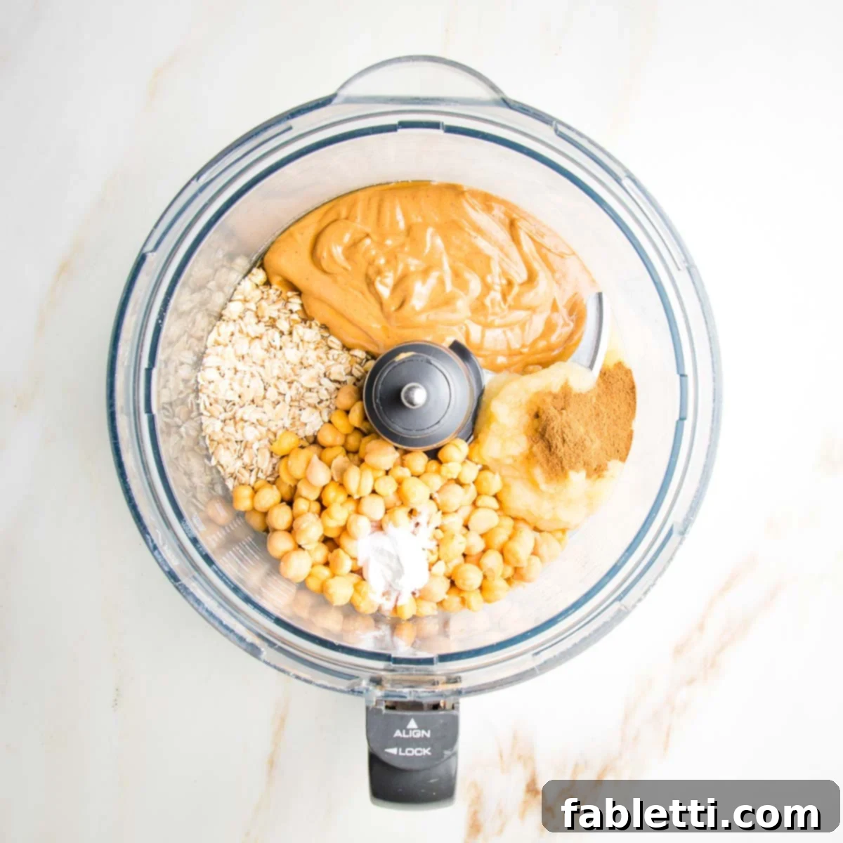 Decadent Vegan Gluten-Free Chocolate Chunk Skillet Cookie 5 Chickpeas, peanut butter, oats, and cinnamon are combined in the bowl of a food processor, ready for blending.